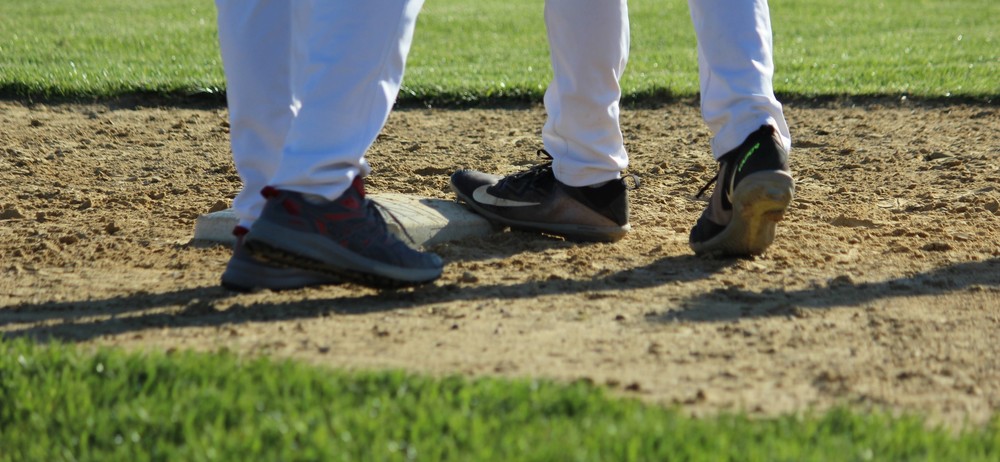 two pairs of feet on a baseball base