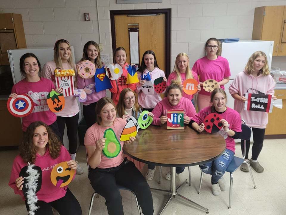 students wearing pink hold up infant costumes