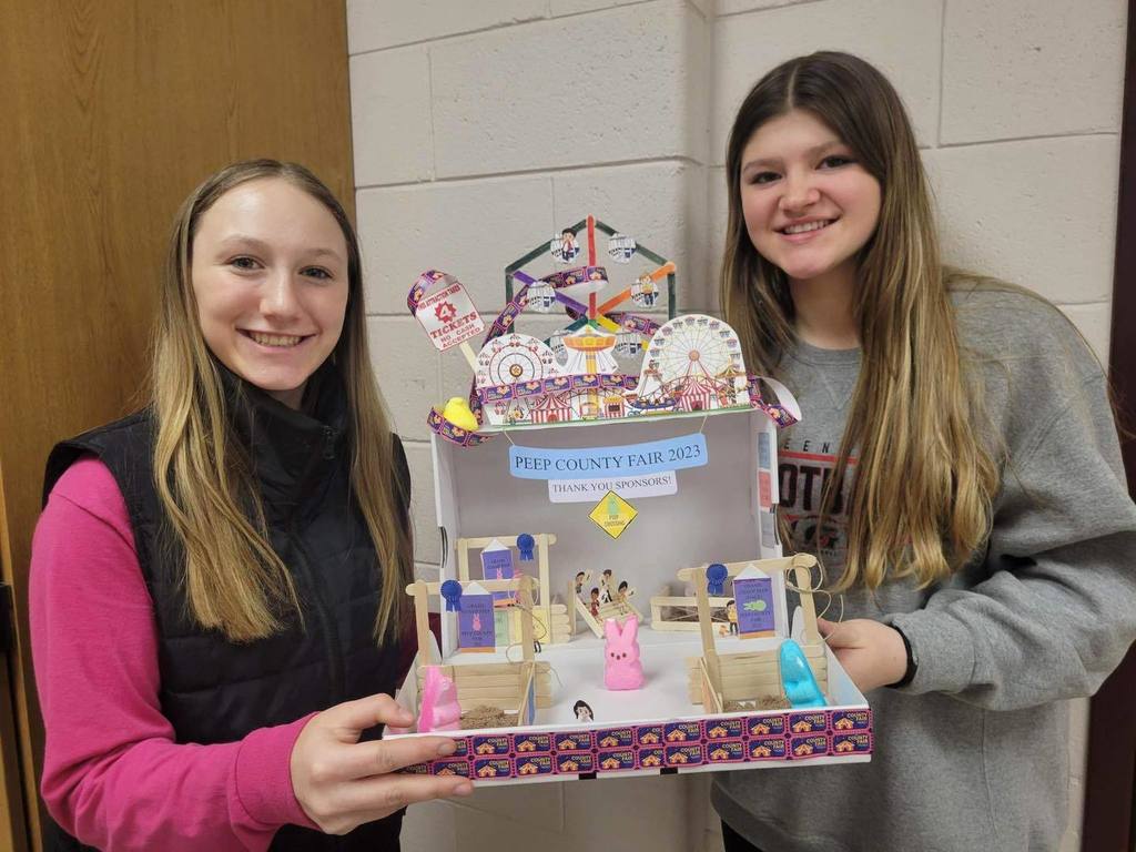 two girls hold a diorama